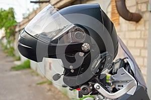 Motorcyclist`s crash-helmet hanging on the handle of a motorcycle. Helmet hanging on the steering wheel on a motorcycle