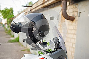 Motorcyclist`s crash-helmet hanging on the handle of a motorcycle. Helmet hanging on the steering wheel on a motorcycle