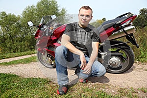 Motorcyclist sitting on country road near bike