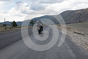 Motorcyclist is traveling by motorcycle on a winding mountain road in summer