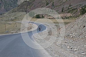 Motorcyclist is traveling by motorcycle on a winding mountain road in summer