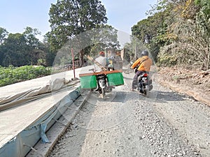 Motorcyclists queue while crossing a road under construction