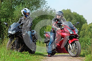 Motorcyclists standing on road looks on each other