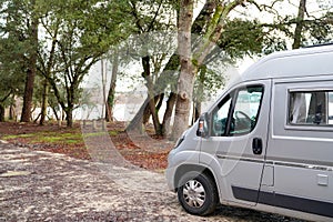 Motorhome at lac d`hourtin under the pine trees of the forest in vanlife concept camper van