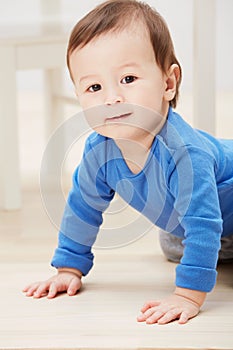 Motoring around the house. Closeup portrait of an adorable baby boy crawling on the floor and smiling at the camera.