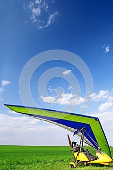 Motorized hang glider over green grass