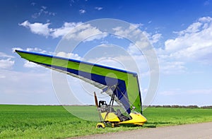 Motorized hang glider over green grass