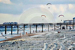 The motorized kites fly over the ocean pier as a group