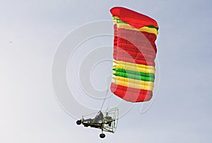 Motorized paraglider in flight riding towards the sun
