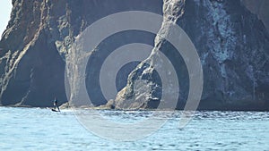 A motorized surfboard with a rider moving on a calm sea. The silhouette of a man on a water scooter glides through the