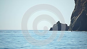 A motorized surfboard with a rider moving on a calm sea. The silhouette of a man on a water scooter glides through the