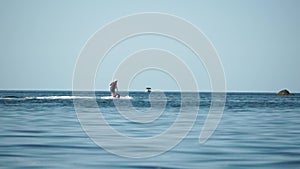 A motorized surfboard with a rider moving on a calm sea. The silhouette of a man on a water scooter glides through the