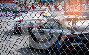 Motorsport car racing on asphalt road. View from the fence mesh netting on blurred car on racetrack background. Super racing car