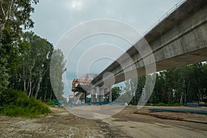 Motorway bridge construction on a dull day. Making a new concrete bridge over a river, view of construction site