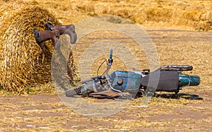 A motorycle near the haystack and boots in the pile of straw. crash humor concept decoration