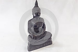 Moulded buddha idol in complete black color in a white backdrop. Macro with extremely shallow depth of field