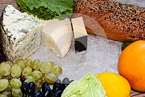 Mouldy cheese with grapes, bread, lettuce and citrus