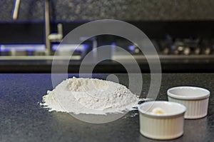 Mound of wheat flour on top of black granite table, preparation of pizza dough