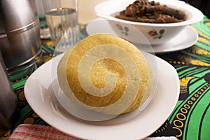 A mound of yellow Garri or Eba placed on a white plate