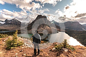 Mount Assiniboine with traveler man standing on Niblet peak in the evening at provincial park