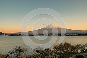 Mount Fuji with snow capped, twilight sky and beautiful Cherry Blossom or pink Sakura flower tree in Spring Season at Lake