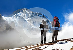 Mount Makalu with clouds and silhouette of two hikers