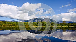 Mount Si reflects in Borst Lake with white parly cloudy sky in spring photo