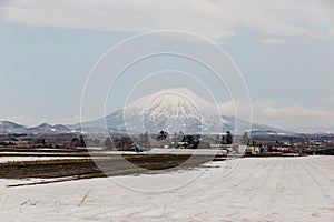 Mount Yotei inactive stratovolcano with village and snow cover on the ground in winter in Hokkaido, Japan