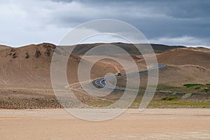 A mountain asphalt road leads to mountains in the volcanic zone in northern Iceland.