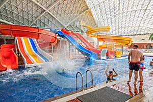 Mountain Beach Water Park in Gorky Gorod resort. Interior view with people bathing in pool by water hills