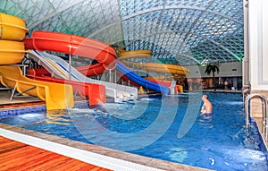 Mountain Beach Water Park in Gorky Gorod resort. Interior view with people bathing in pool by water hills