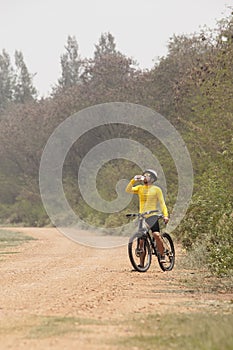 Mountain bicycle man drinking fresh water from bottle on dirt tr
