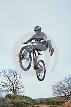 Mountain, bike jump and person cycling on bicycle for extreme sports competition stunt or training in nature. Skill