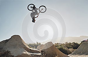 Mountain bike jump training man on rocks hill cycling in air, blue sky mockup for professional performance, training or