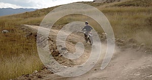 A mountain bike rider rides fast on a muddy, dusty road in the mountains. Off-road adventures of extreme riders.