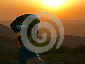 Mountain bike - woman with a bicycle helmet admiring the sunset