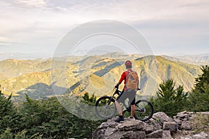 Mountain biker looking at view on bike trail in autumn mountains