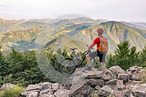 Mountain biker looking at view on bike trail in autumn mountains