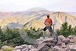 Mountain biker looking at view on bike trail in autumn mountains