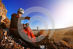 Mountain biker looking at view on bike trail in spring landscape. Male rider resting on cycling trip in nature.