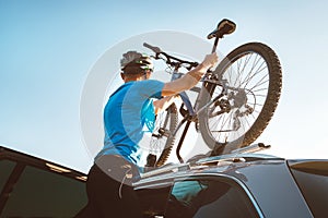 Mountain biker man take of his bike fron the car roof