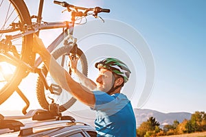 Mountain biker man take of his bike fronm the car roof. Active sport people concept image