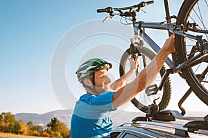 Mountain biker man take of his bike fronm the car roof. Active sport people concept image