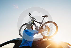 Mountain biker man takes of his bike from the car roof