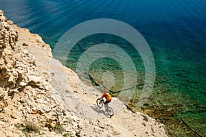 Mountain biker riding a bike on rocky trail path at sea