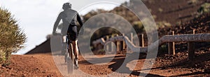 Mountain biker riding on bike singletrack trail, back view of mountain biker