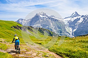 Mountain biker riding downhill in the Swiss Alps. Famous mountains Jungfrau, Eiger and Monch in the background. Mountain biking,