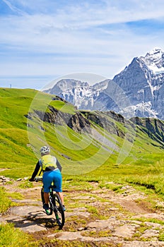 Mountain biker riding downhill in the Swiss Alps. Famous mountains Jungfrau, Eiger and Monch in the background. Mountain biking,