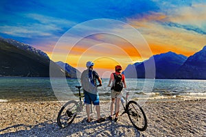 Mountain biking, couple with bikes at sunset on Lake Garda, Riva del Garda, Italy
