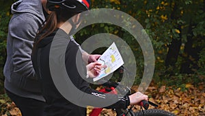 Mountain biking couple looking at map in the forest on a sunny day